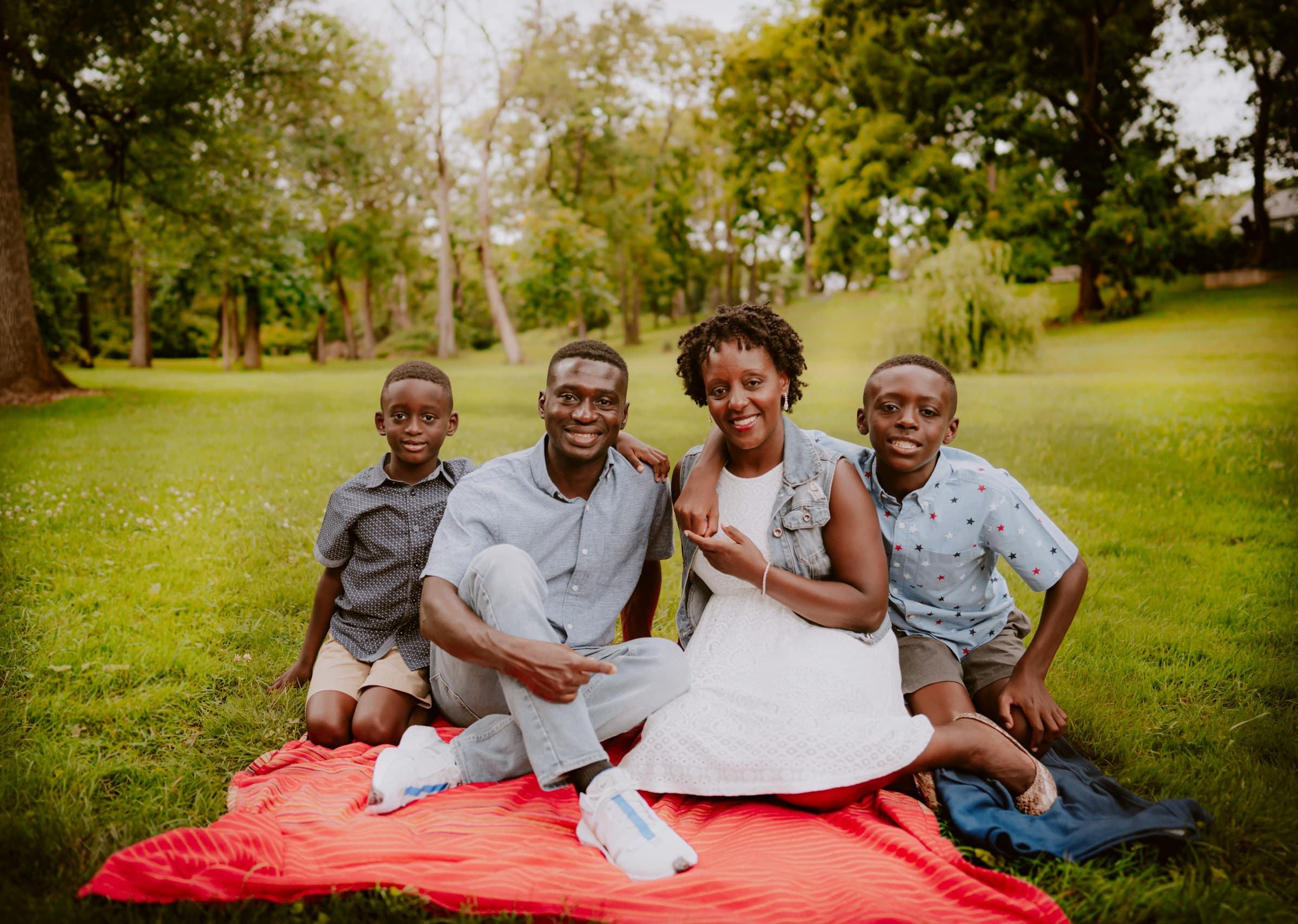 A family sitting together outdoors on a blanket.